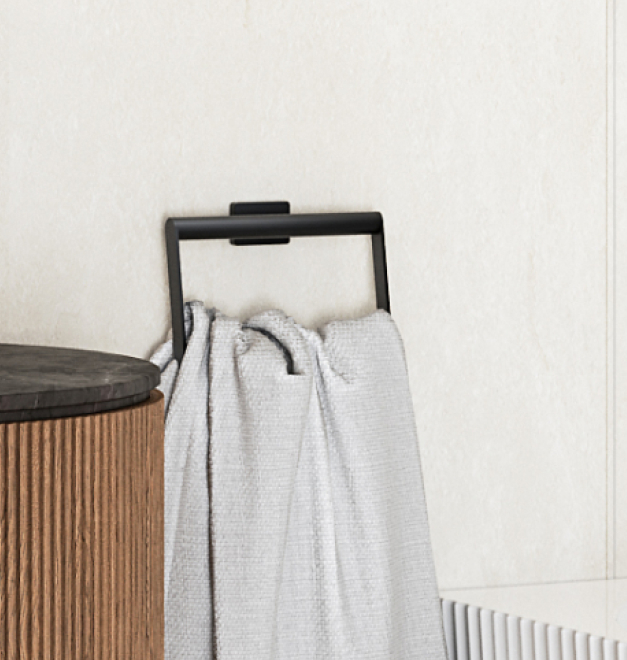 Czarny uchwyt na ręcznik Ferro Greta z białym ręcznikiem, zamontowany na beżowej ścianie obok drewnianej szafki.